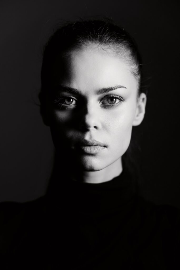 Intense portrait of a young woman with striking features against a dark background, showcasing